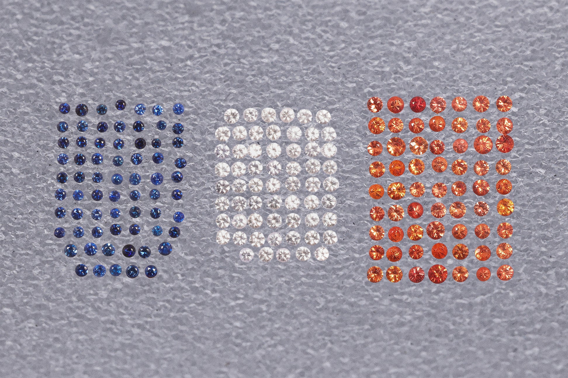 A GROUP OF UNMOUNTED BLUE, WHITE AND ORANGE SAPPHIRE MELEES