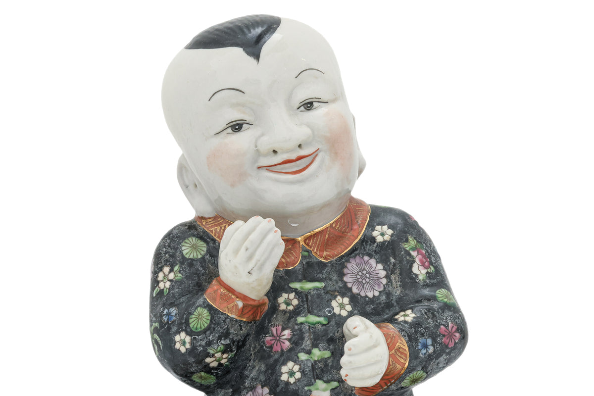 A CHINESE CERAMIC FIGURE OF A SEATED BOY