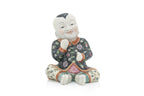 A CHINESE CERAMIC FIGURE OF A SEATED BOY