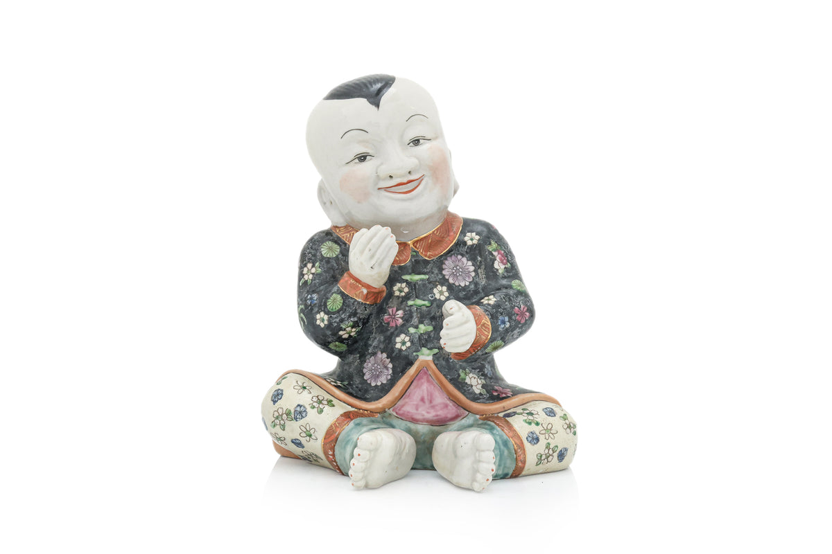 A CHINESE CERAMIC FIGURE OF A SEATED BOY